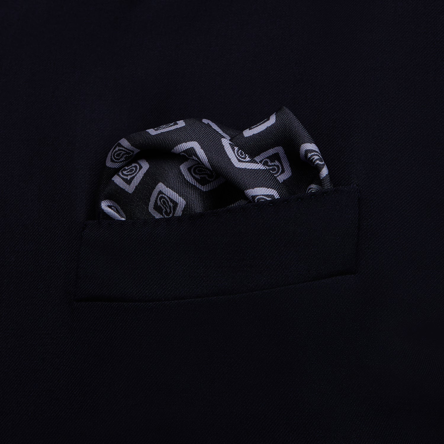 View 3 of product The Turnbull & Asser Navy Cubed Paisley Silk Pocket Square features a dark navy base with a repeating white square and diamond pattern, finished with a geometric border and “Turnbull & Asser” in the corners.