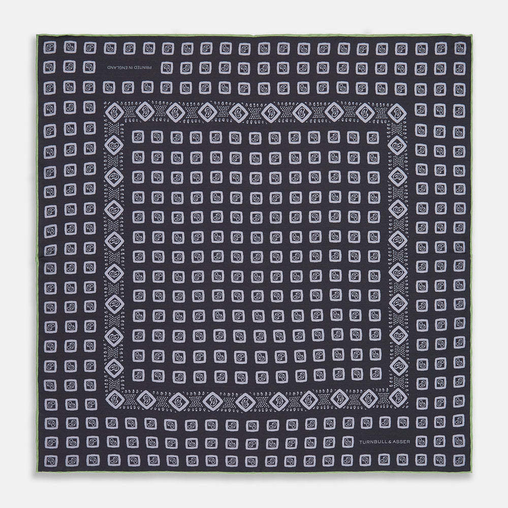 The Turnbull & Asser Navy Cubed Paisley Silk Pocket Square features a dark navy base with a repeating white square and diamond pattern, finished with a geometric border and “Turnbull & Asser” in the corners.