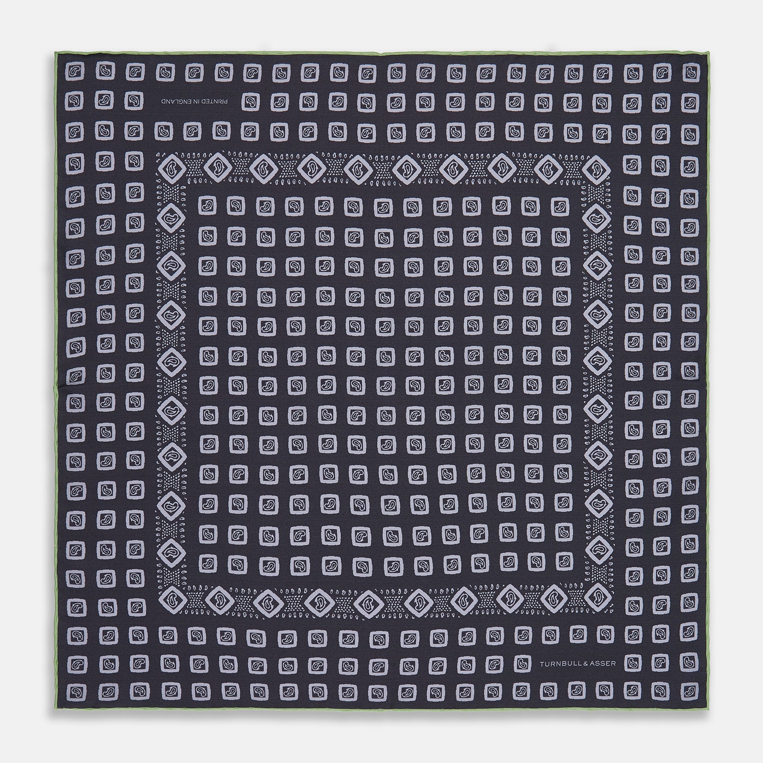 View 1 of product The Turnbull & Asser Navy Cubed Paisley Silk Pocket Square features a dark navy base with a repeating white square and diamond pattern, finished with a geometric border and “Turnbull & Asser” in the corners.