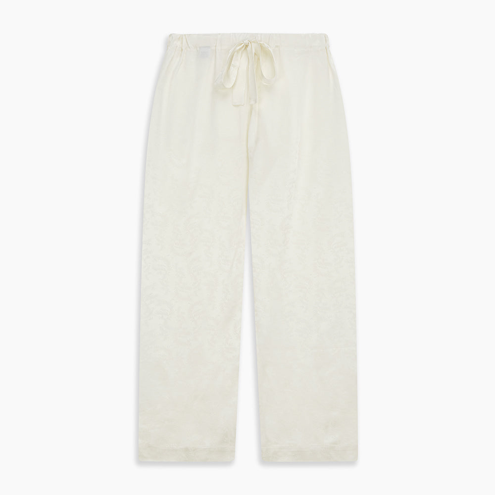 The Cream Floral Pattern Silk Harriet Women's Pyjama Set by Turnbull & Asser features long sleeves, pants, dark piping, a chest pocket, and luxurious silk fabric with a cream floral design, shown on a plain white background.