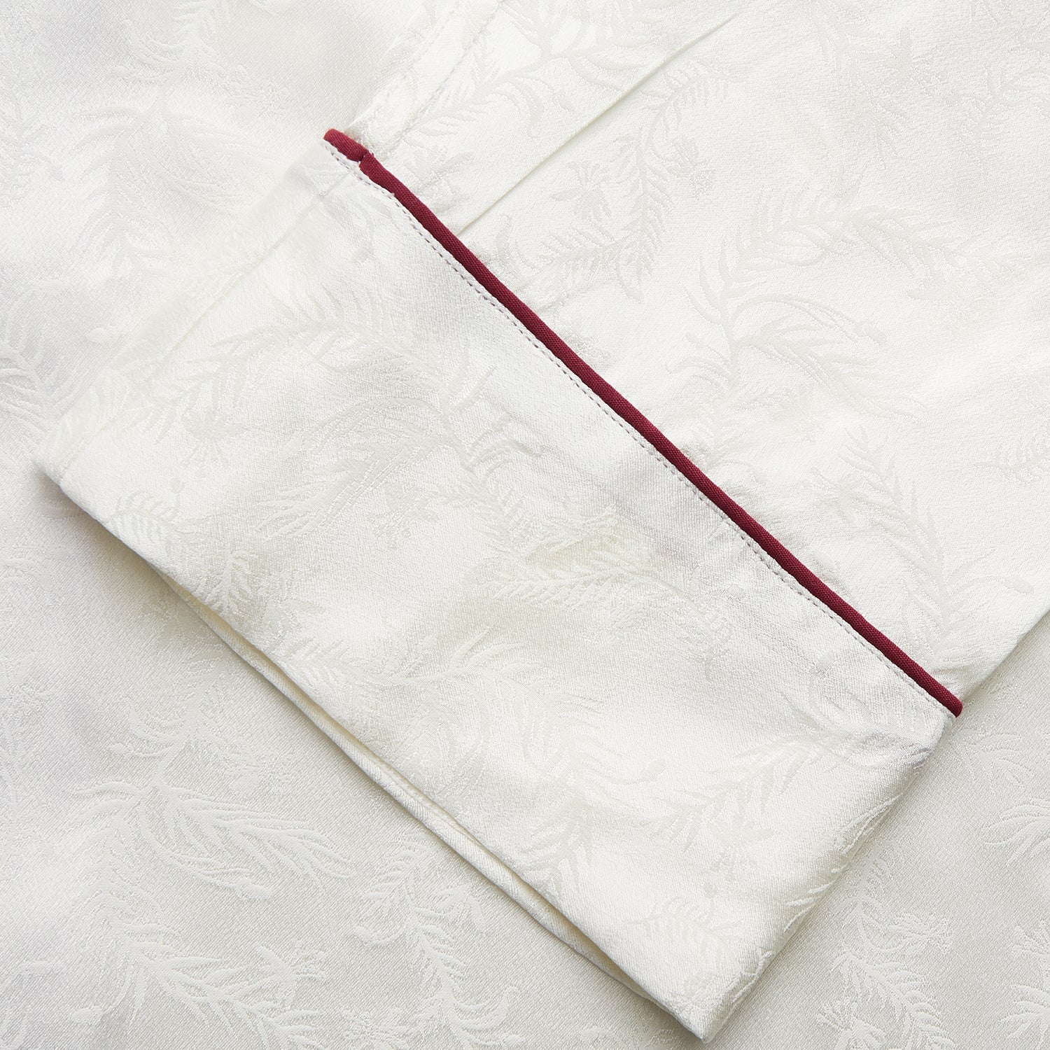View 4 of product The Cream Floral Pattern Silk Harriet Women's Pyjama Set by Turnbull & Asser features long sleeves, pants, dark piping, a chest pocket, and luxurious silk fabric with a cream floral design, shown on a plain white background.