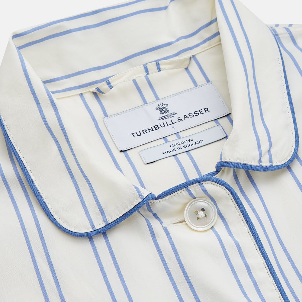 The Turnbull & Asser Women's Blue Multi Cotton Thelma Pyjama Set features a long-sleeve button-up shirt with collar and pocket, plus matching drawstring pants, elegantly displayed against a white background.