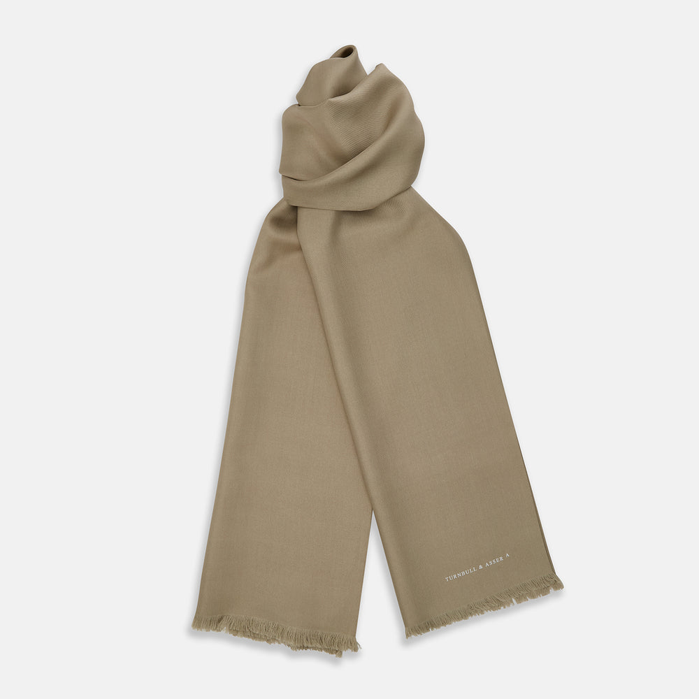 The Khaki Silk Twill Lawton Scarf by Turnbull & Asser, an essential accessory, features fringed edges and is neatly folded on a white background. A small logo near one end adds a refined Turnbull touch.