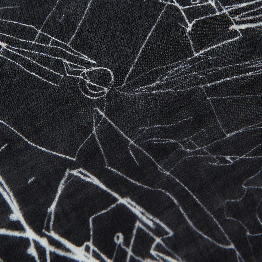 The Turnbull & Asser Black Sketched Pattern Wool Chilcott Scarf features white abstract lines, frayed edges, and is shown loosely knotted on a light gray background.