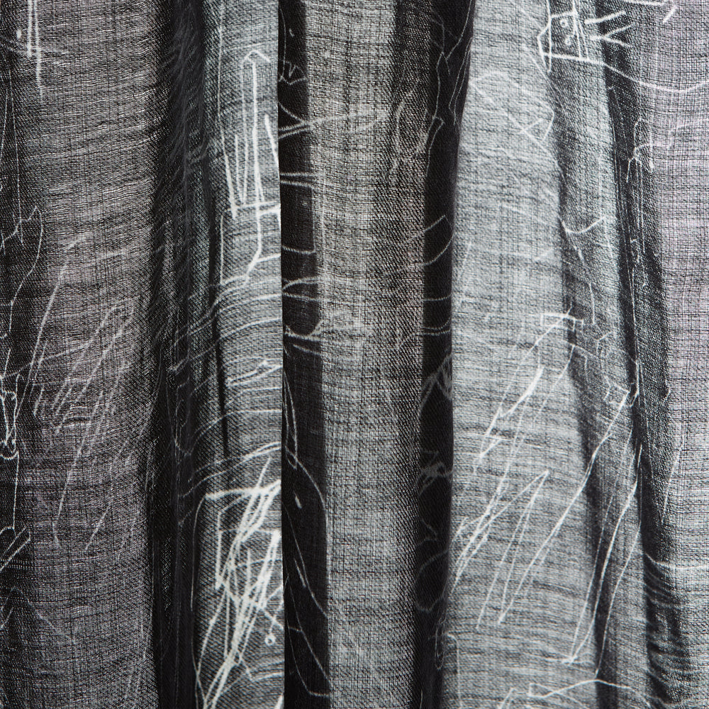 The Turnbull & Asser Black Sketched Pattern Wool Chilcott Scarf features white abstract lines, frayed edges, and is shown loosely knotted on a light gray background.
