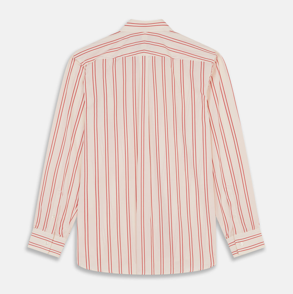 A man poses against a beige backdrop in the Turnbull & Asser Red and Off-White Stripe Cotton Weekend Fit Finch Shirt, styled with dark blue jeans and a brown belt for a timeless look. One hand rests in his pocket as he faces slightly to the side.