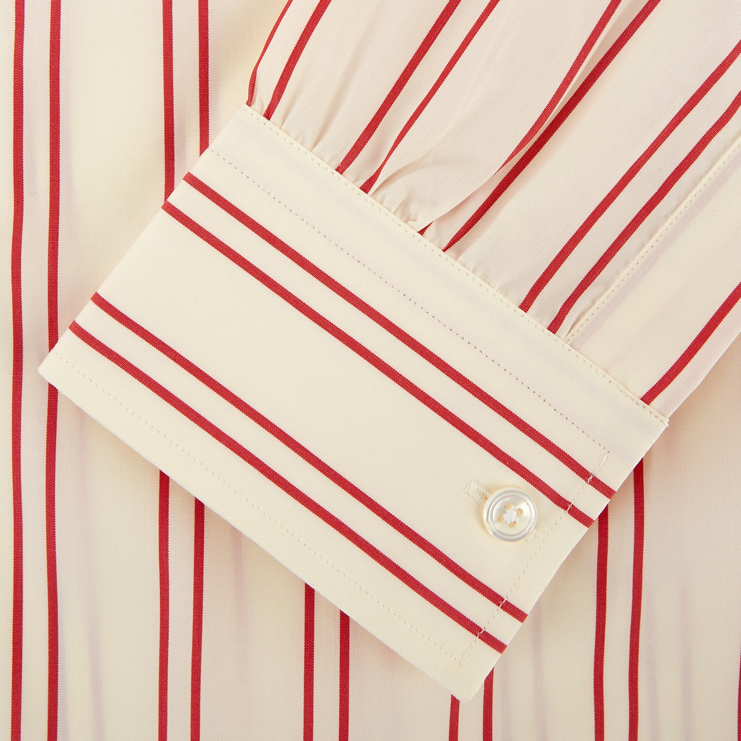 View 4 of product A man poses against a beige backdrop in the Turnbull & Asser Red and Off-White Stripe Cotton Weekend Fit Finch Shirt, styled with dark blue jeans and a brown belt for a timeless look. One hand rests in his pocket as he faces slightly to the side.
