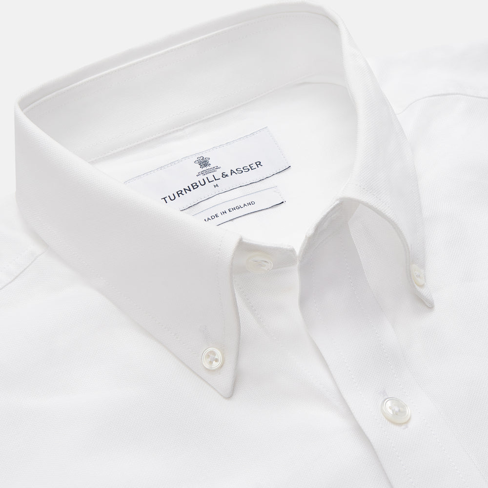 The Turnbull & Asser White Cotton Voile Weekend Fit Nevis Shirt features a Dorset button-down collar, two chest pockets, and a subtle military-inspired design, shown against a plain white background.