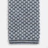View 2 of product The Turnbull & Asser Pale Blue Multi Cashmere Knitted Tie features a subtle checkered pattern in black and light blue, making it a refined addition to your menswear collection. Shown rolled up on a plain white background.