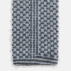 View 4 of product The Turnbull & Asser Pale Blue Multi Cashmere Knitted Tie features a subtle checkered pattern in black and light blue, making it a refined addition to your menswear collection. Shown rolled up on a plain white background.