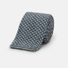 View 1 of product The Turnbull & Asser Pale Blue Multi Cashmere Knitted Tie features a subtle checkered pattern in black and light blue, making it a refined addition to your menswear collection. Shown rolled up on a plain white background.