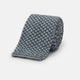 The Turnbull & Asser Pale Blue Multi Cashmere Knitted Tie features a subtle checkered pattern in black and light blue, making it a refined addition to your menswear collection. Shown rolled up on a plain white background.