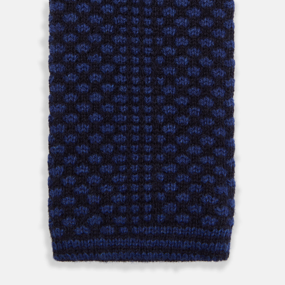 The Turnbull & Asser Navy Multi Cashmere Knitted Tie features a subtle black checkered pattern and is shown rolled up against a plain light background.
