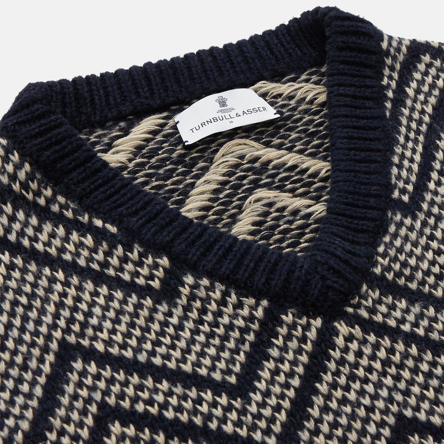 View 2 of product The Turnbull & Asser Navy and White Wool Blend Albion Chunky Slipover is a sleeveless knitted vest with ribbed V-neck, armholes, and hem, featuring a bold chevron pattern.