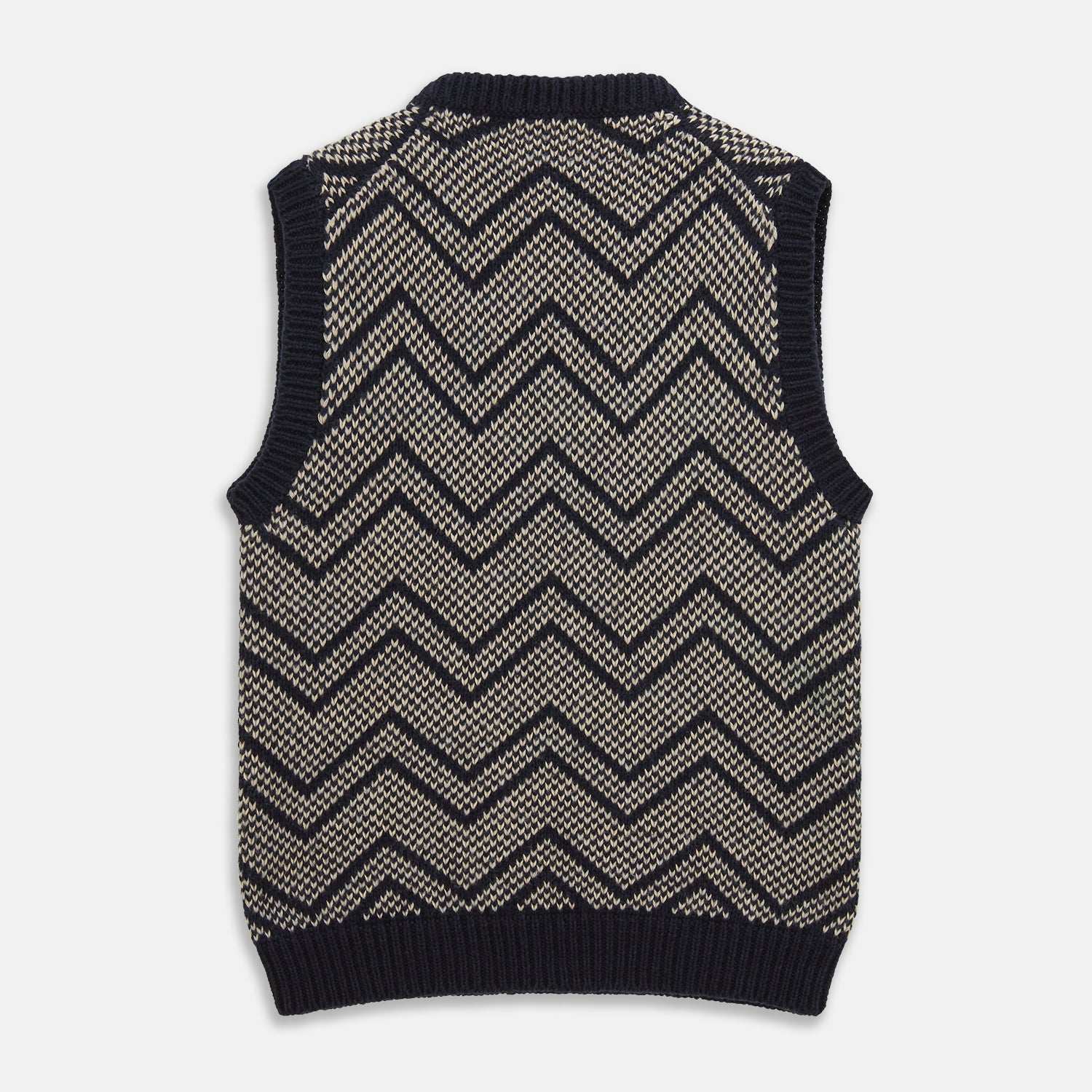 View 3 of product The Turnbull & Asser Navy and White Wool Blend Albion Chunky Slipover is a sleeveless knitted vest with ribbed V-neck, armholes, and hem, featuring a bold chevron pattern.