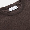 View 2 of product The Turnbull & Asser Brown Cashmere Glenn Jumper is a classic menswear piece with a crew neck and ribbed cuffs, collar, and hem. It’s laid flat on a white background, showcasing its timeless long-sleeved design.