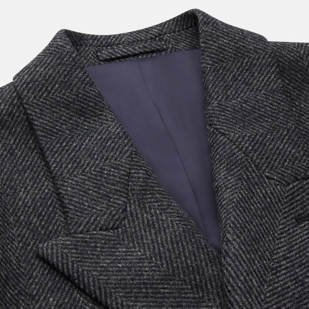 The Grey Herringbone Wool Double Breasted Highgrove Overcoat by Turnbull & Asser features black buttons, a notched lapel, and side pockets, shown against a plain white background.