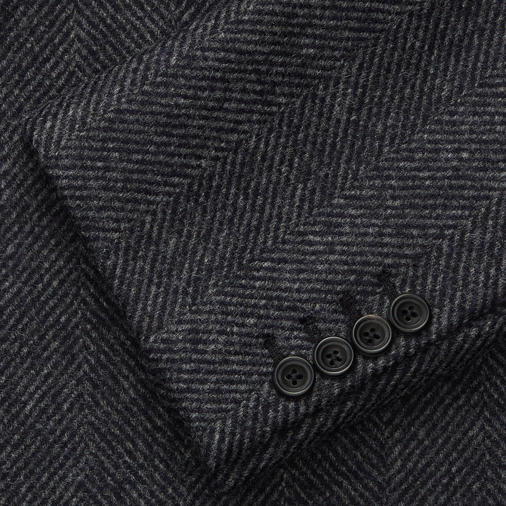 The Grey Herringbone Wool Double Breasted Highgrove Overcoat by Turnbull & Asser features black buttons, a notched lapel, and side pockets, shown against a plain white background.