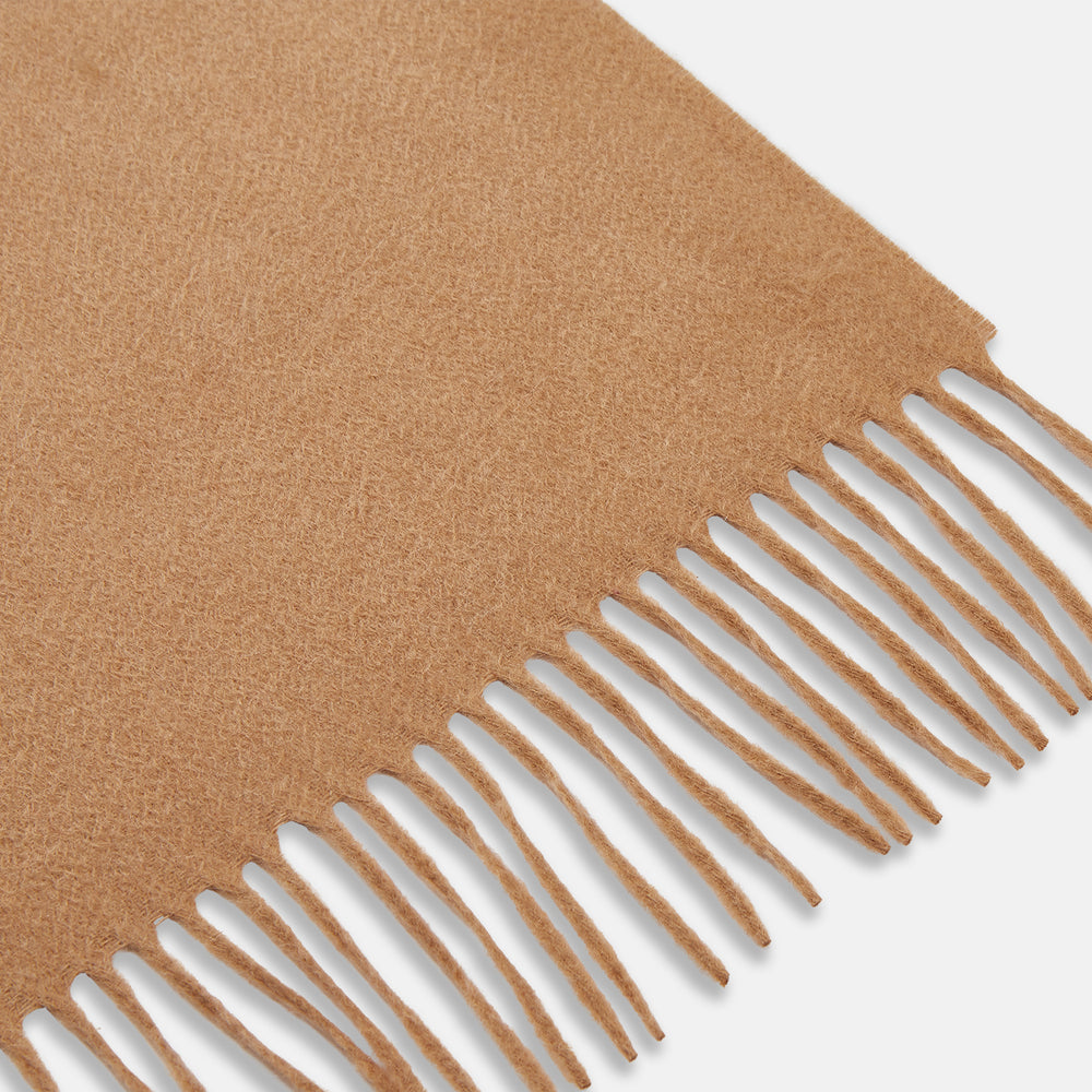 The Turnbull & Asser Camel Brown Cashmere Scarf features soft cashmere and fringed ends, neatly folded on a white background—an essential winter accessory.