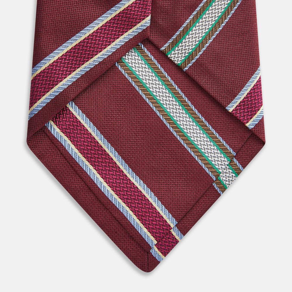 A Turnbull & Asser Burgundy Multi Stripe Silk Tie, featuring diagonal white, green, and blue stripes, is rolled up and displayed on a plain white background.