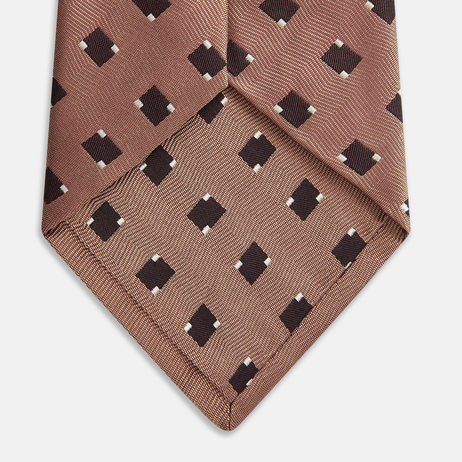 View 3 of product The Bronze and Chocolate Brown Tile Silk Tie by Turnbull & Asser features a classic tile pattern with small black graduation caps, neatly rolled on a plain white background.