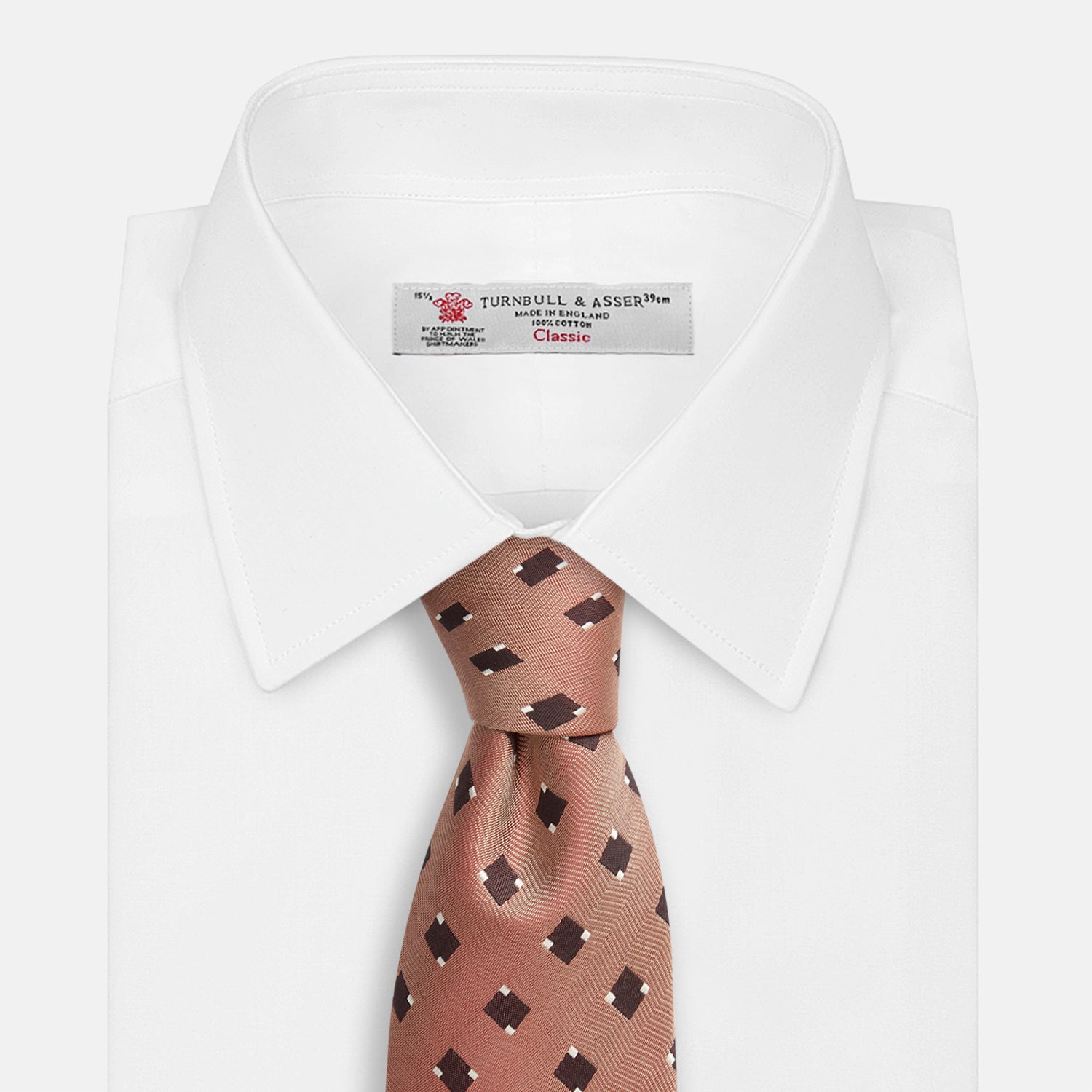 View 4 of product The Bronze and Chocolate Brown Tile Silk Tie by Turnbull & Asser features a classic tile pattern with small black graduation caps, neatly rolled on a plain white background.