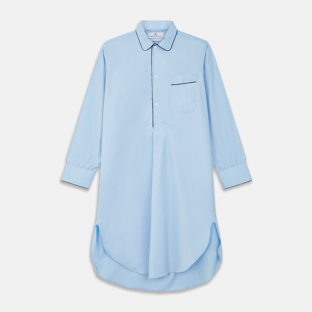 The Turnbull & Asser Light Blue Piped Cotton Nightshirt is a luxurious long-sleeve shirt dress with a pointed collar, black piping on the collar, cuffs, and chest pocket, button front closure, and curved hem.