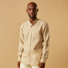 View 1 of product A man with a bald head and trimmed beard wears the Turnbull & Asser Beige Weekend Fit Linen Blake Shirt with stand collar and 1-button cuffs, standing calmly against a matching beige background.