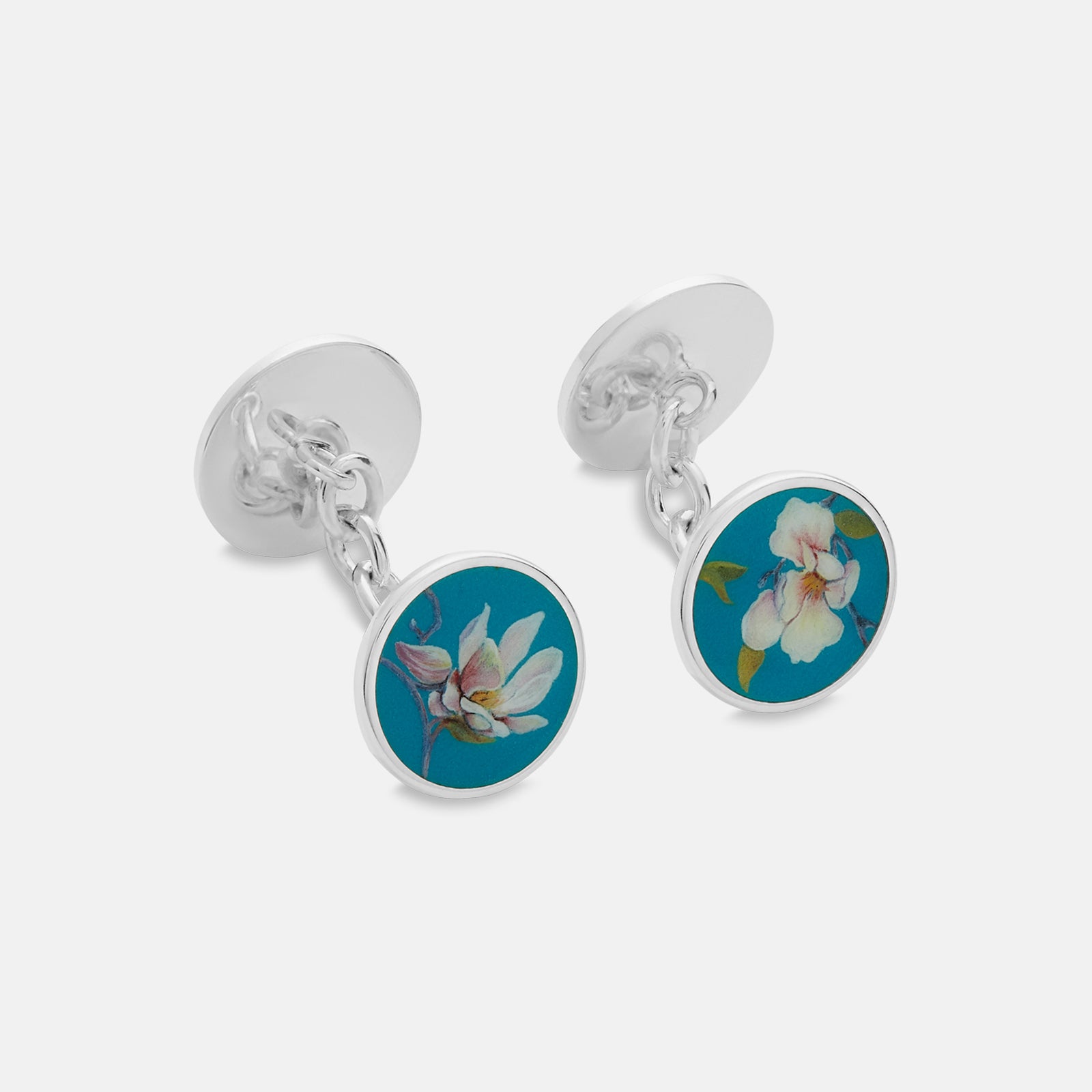 View 1 of product Turnbull & Asser’s Teal Magnolia Hand-painted Cufflinks feature circular sterling silver faces with magnolia designs on a teal background. Each handmade pair is shown on a plain white surface.