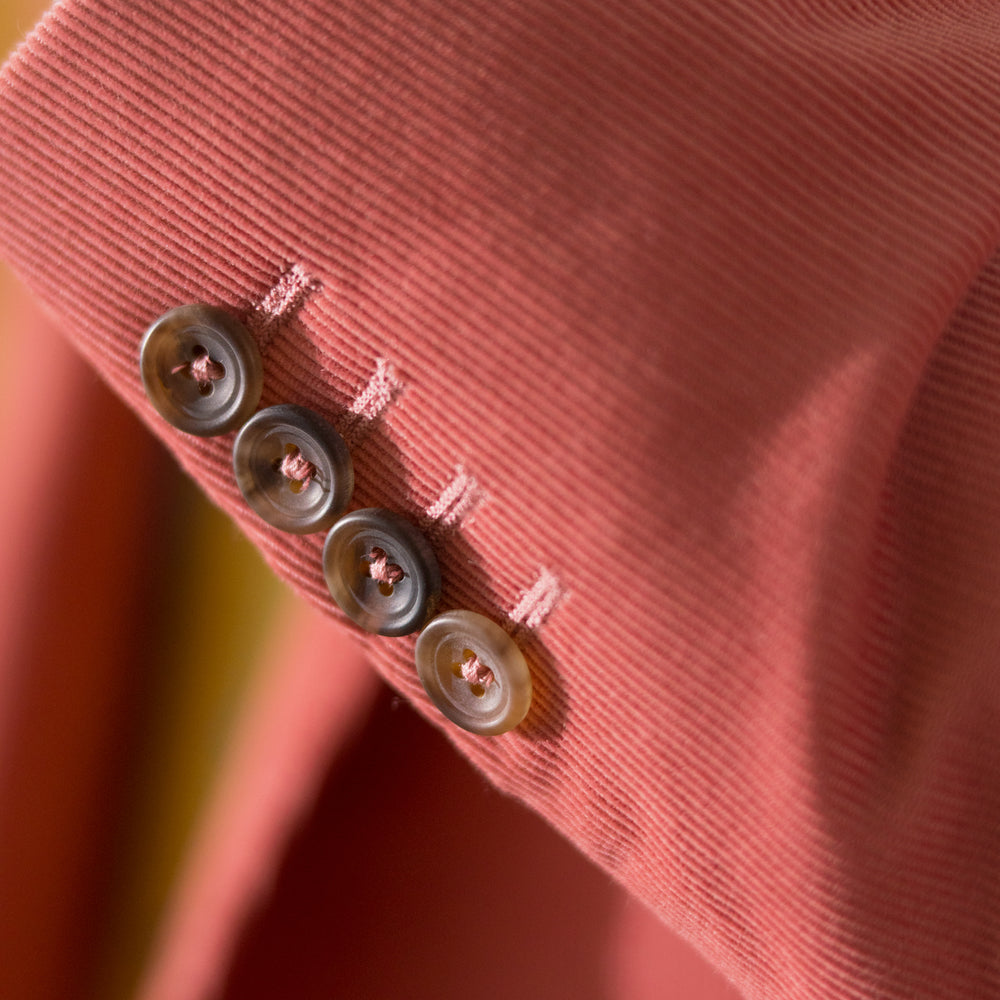 The Turnbull & Asser Pink Cord Bern Blazer features notch lapels, two brown buttons, three front pockets, and buttoned cuffs, showcasing Italian tailoring against a plain white background.