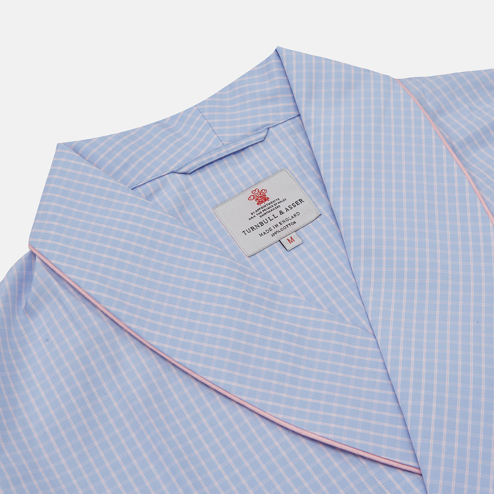 The Turnbull & Asser Blue & Pink Poplin Cotton Check Dressing Gown features a wide collar, pink trim, and a front sash—stylish and compact enough to pack for your next trip.