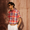View 2 of product The Turnbull & Asser Red Madras Check Weekend Fit Short Sleeve Linen Shirt features a Dorset collar, white buttons, and a red, blue, white, and beige plaid pattern. Shown on a plain white background.