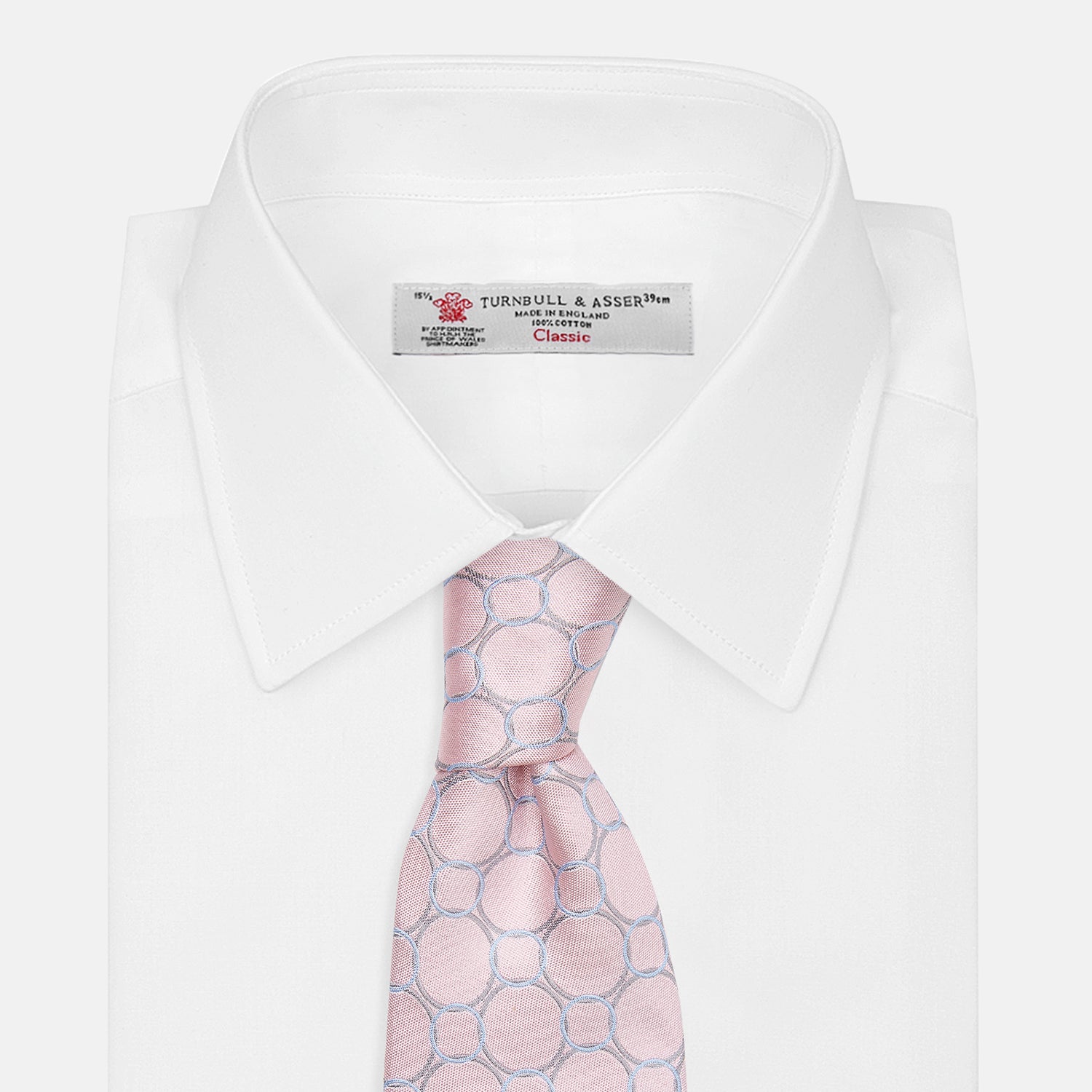 View 4 of product The Turnbull & Asser Baby Pink and Blue Circle Jacquard Silk Tie features a subtle geometric pattern, elegantly rolled against a plain white background.