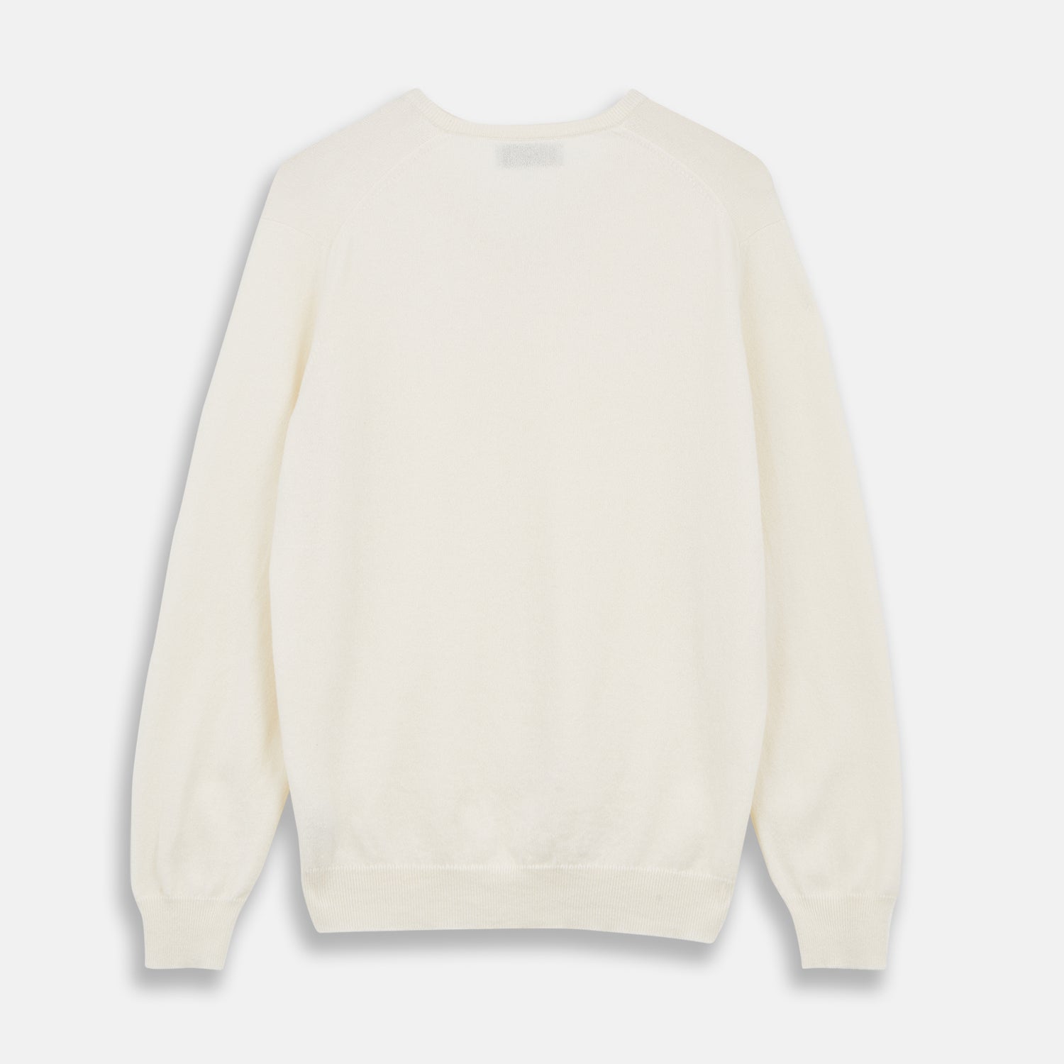 View 3 of product The Turnbull & Asser Cream Cashmere V-Neck Jumper is a luxury knitwear piece with ribbed cuffs and hem, shown laid flat on a white background. Its classic long-sleeve style offers timeless elegance.