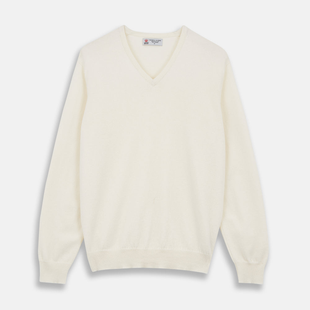 The Turnbull & Asser Cream Cashmere V-Neck Jumper is a luxury knitwear piece with ribbed cuffs and hem, shown laid flat on a white background. Its classic long-sleeve style offers timeless elegance.