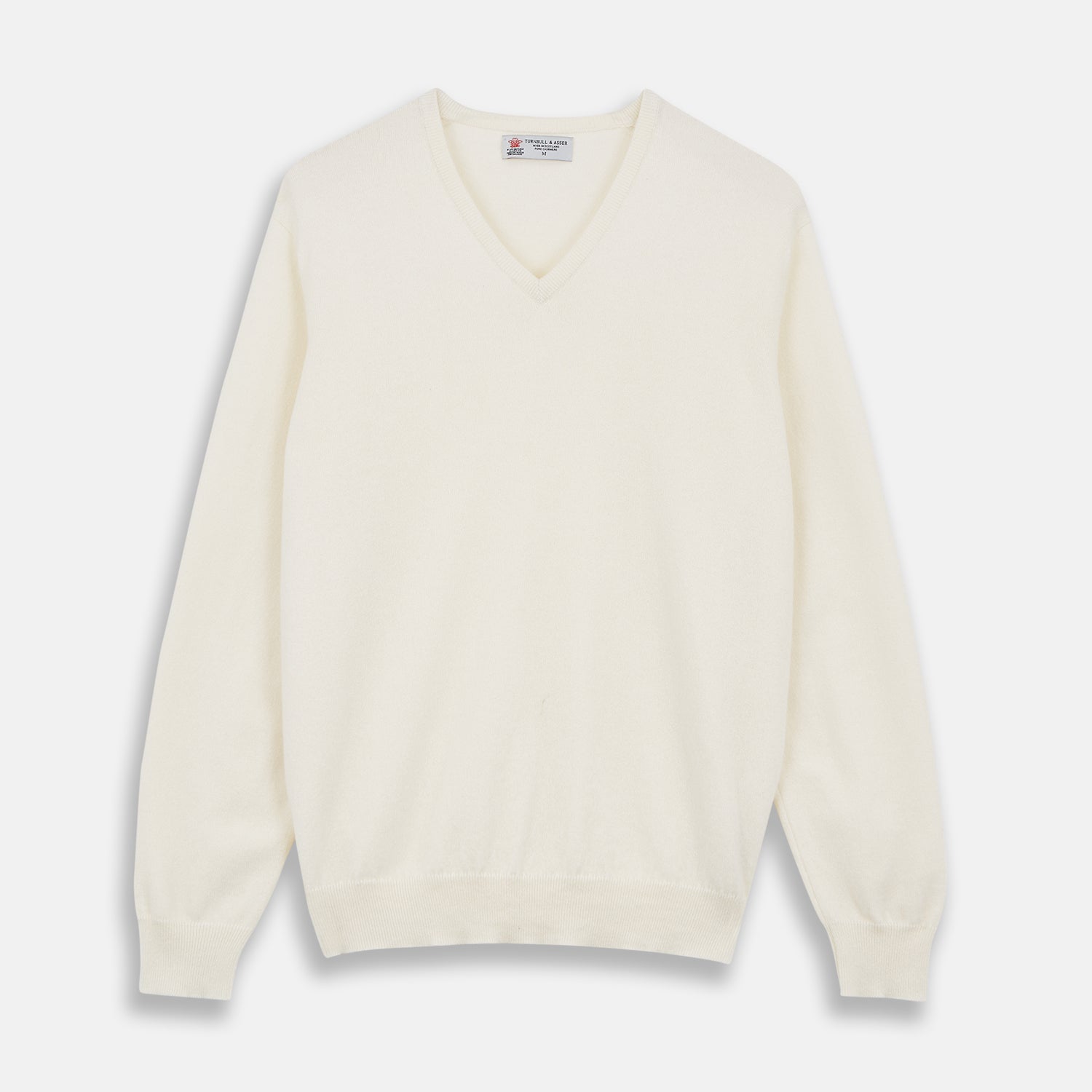 View 1 of product The Turnbull & Asser Cream Cashmere V-Neck Jumper is a luxury knitwear piece with ribbed cuffs and hem, shown laid flat on a white background. Its classic long-sleeve style offers timeless elegance.