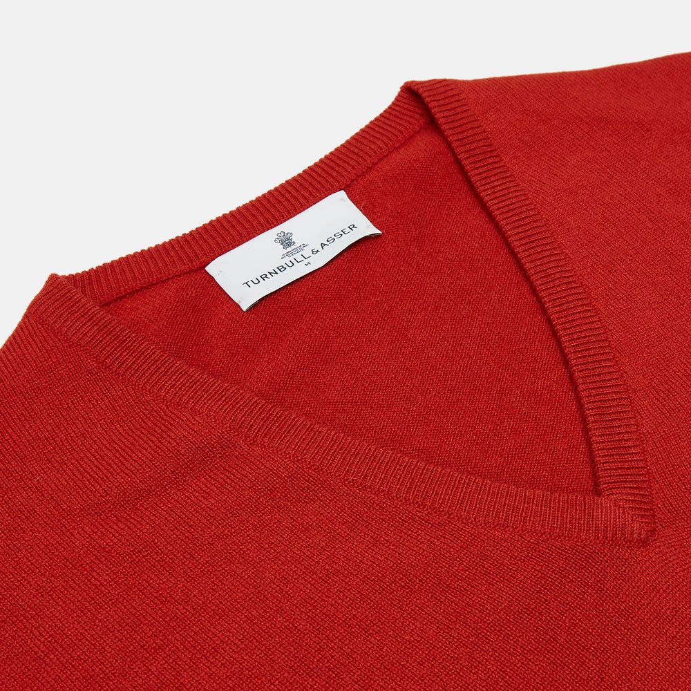 The Turnbull & Asser Red Cashmere V-Neck Jumper features long sleeves and ribbed cuffs and hem, shown laid flat on a white background.
