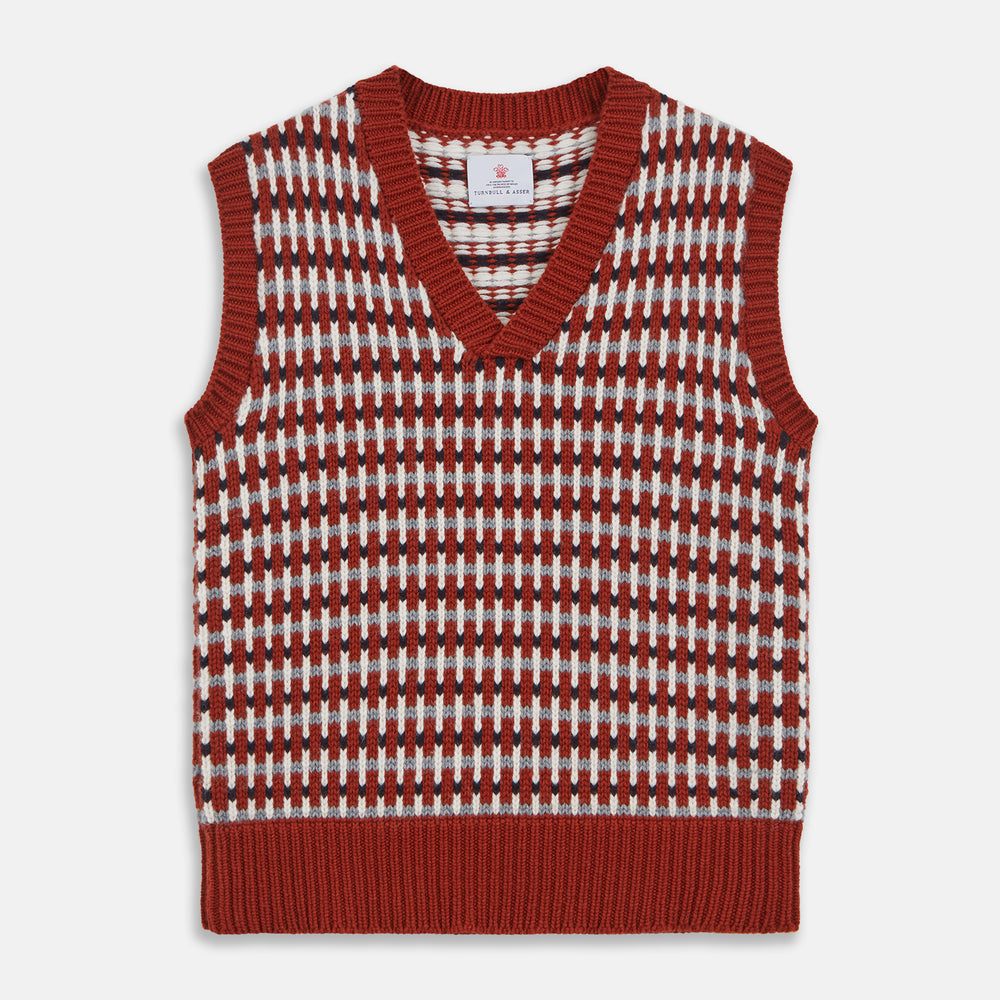 The Rust Knitted Cashmere Slipover by Turnbull & Asser is a sleeveless V-neck vest in red, white, and dark brown houndstooth, inspired by Welsh knitwear with solid red ribbed trim at the collar, armholes, and hem.
