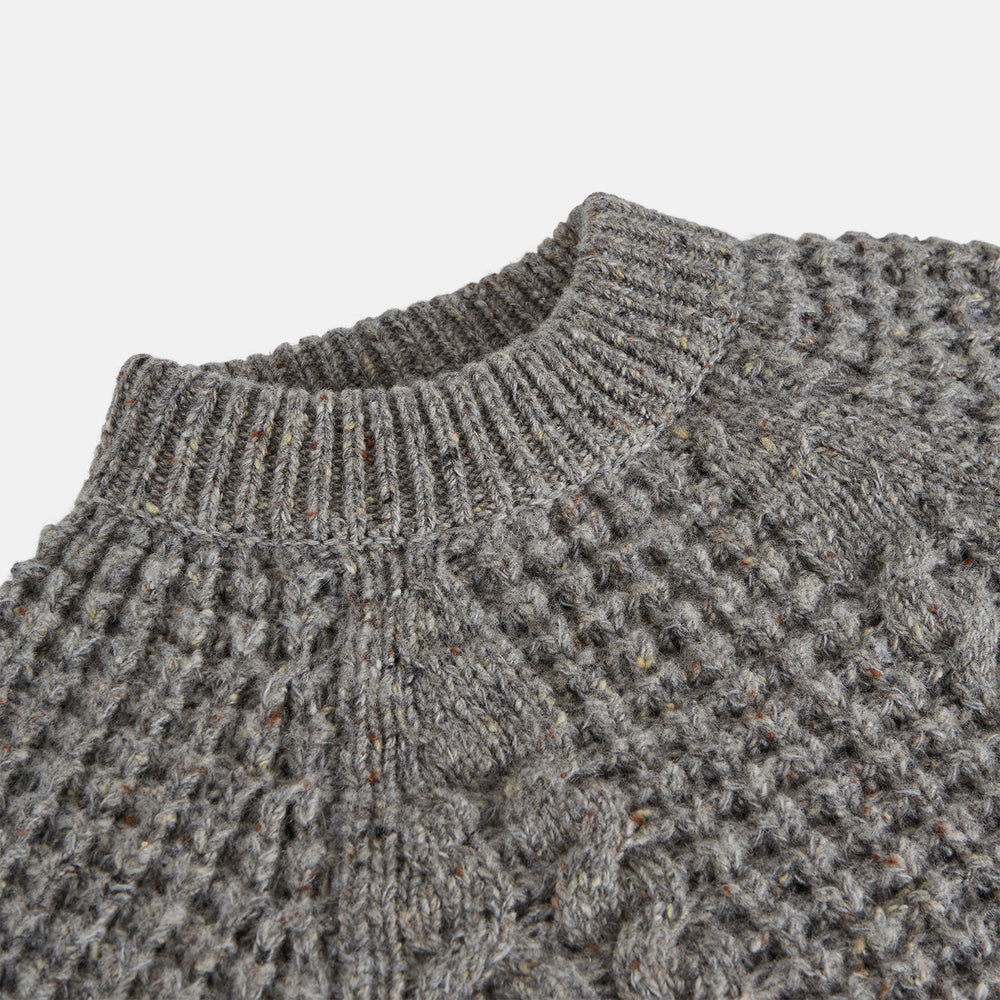 The Turnbull & Asser Merino Knitted Raglan Sleeve Crewneck Jumper in gray features intricate front and sleeve knit patterns, a high neckline, and long sleeves—an essential piece of men’s knitwear. Laid flat on a white background.