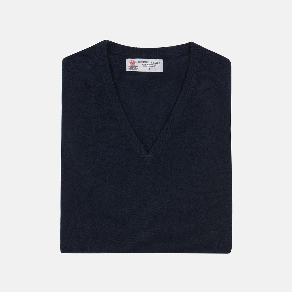 A neatly folded Turnbull & Asser Navy V-Neck Cashmere Slipover is displayed on a plain white background, its inner neckline label visible.