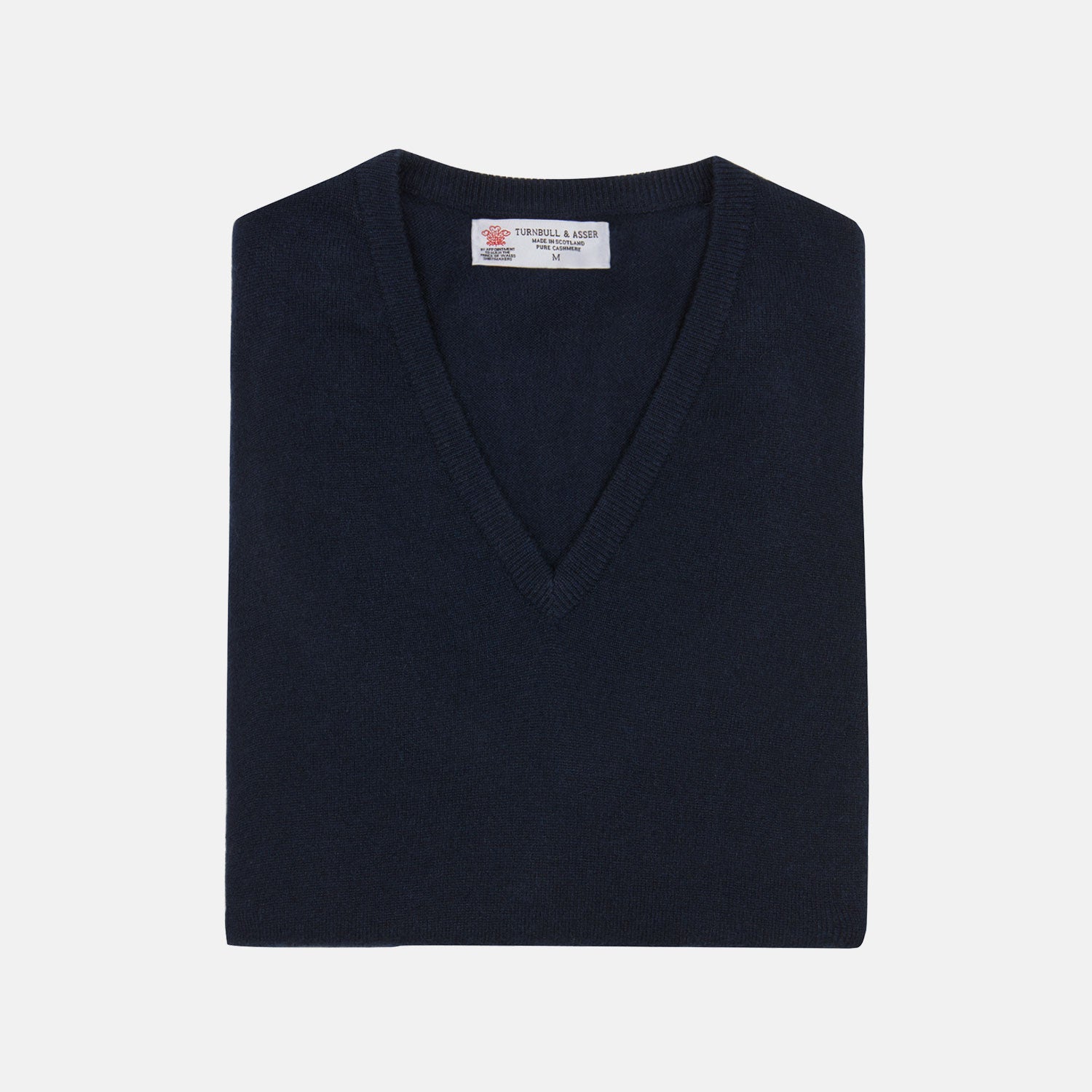 View 1 of product A neatly folded Turnbull & Asser Navy V-Neck Cashmere Slipover is displayed on a plain white background, its inner neckline label visible.