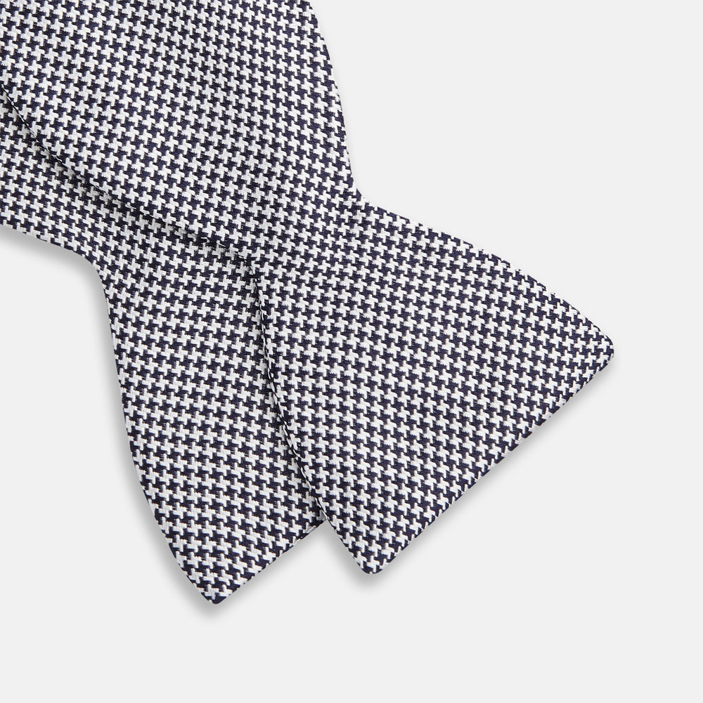 The Turnbull & Asser Black Houndstooth Silk Bow Tie features a classic black and white pattern, displayed against a plain white background—an elegant choice to elevate any formal ensemble.