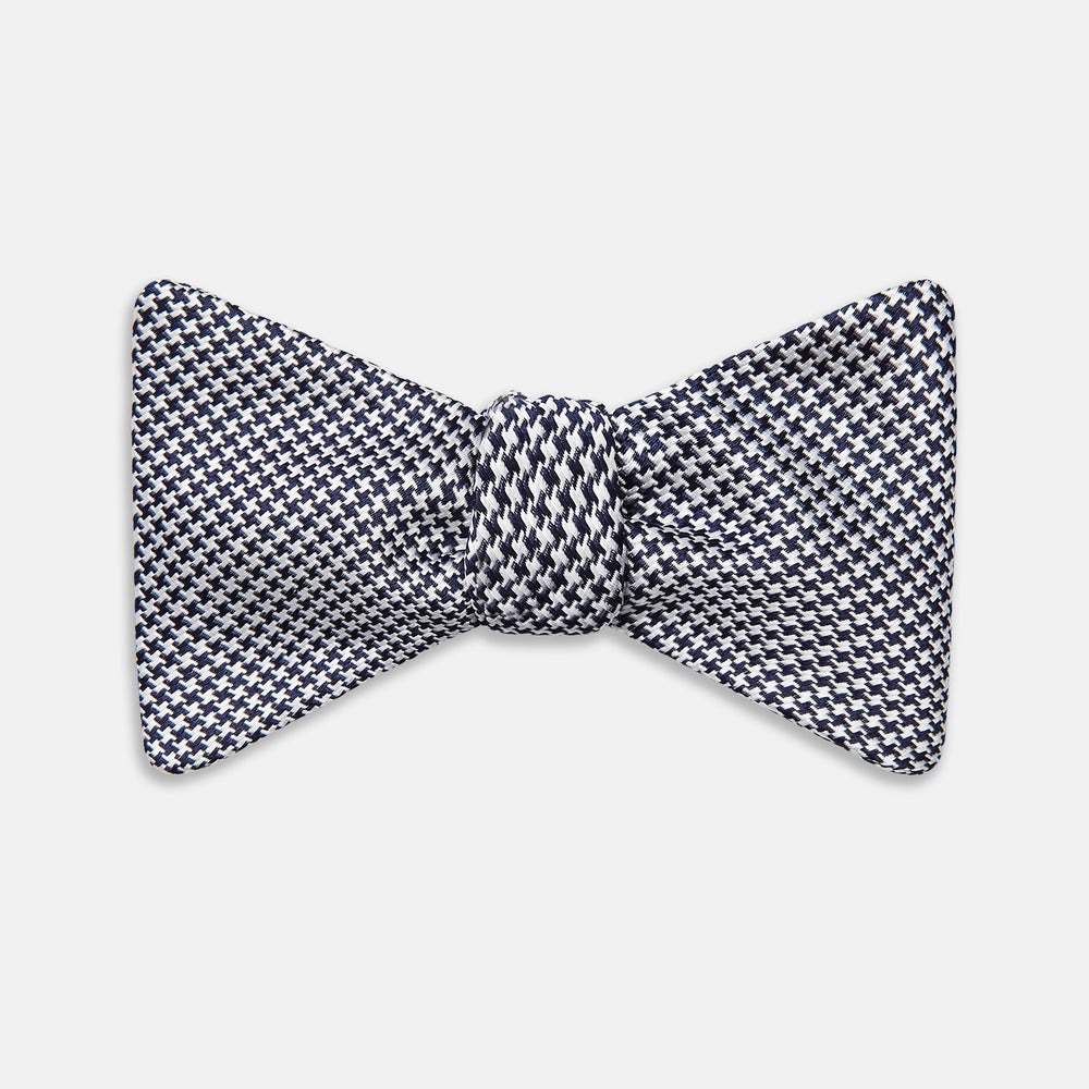 The Turnbull & Asser Black Houndstooth Silk Bow Tie features a classic black and white pattern, displayed against a plain white background—an elegant choice to elevate any formal ensemble.