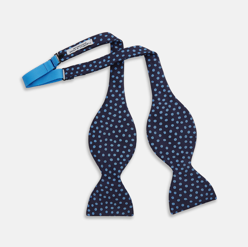 The Turnbull & Asser Navy and Blue Paint Spot Silk Bow Tie features a refined pattern of blue dots on navy, making it an essential addition to any men's accessories collection. Photographed on a plain white background.