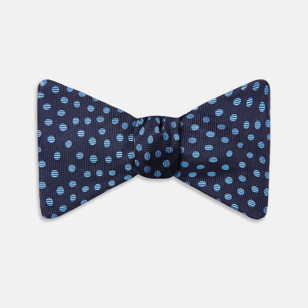 The Turnbull & Asser Navy and Blue Paint Spot Silk Bow Tie features a refined pattern of blue dots on navy, making it an essential addition to any men's accessories collection. Photographed on a plain white background.
