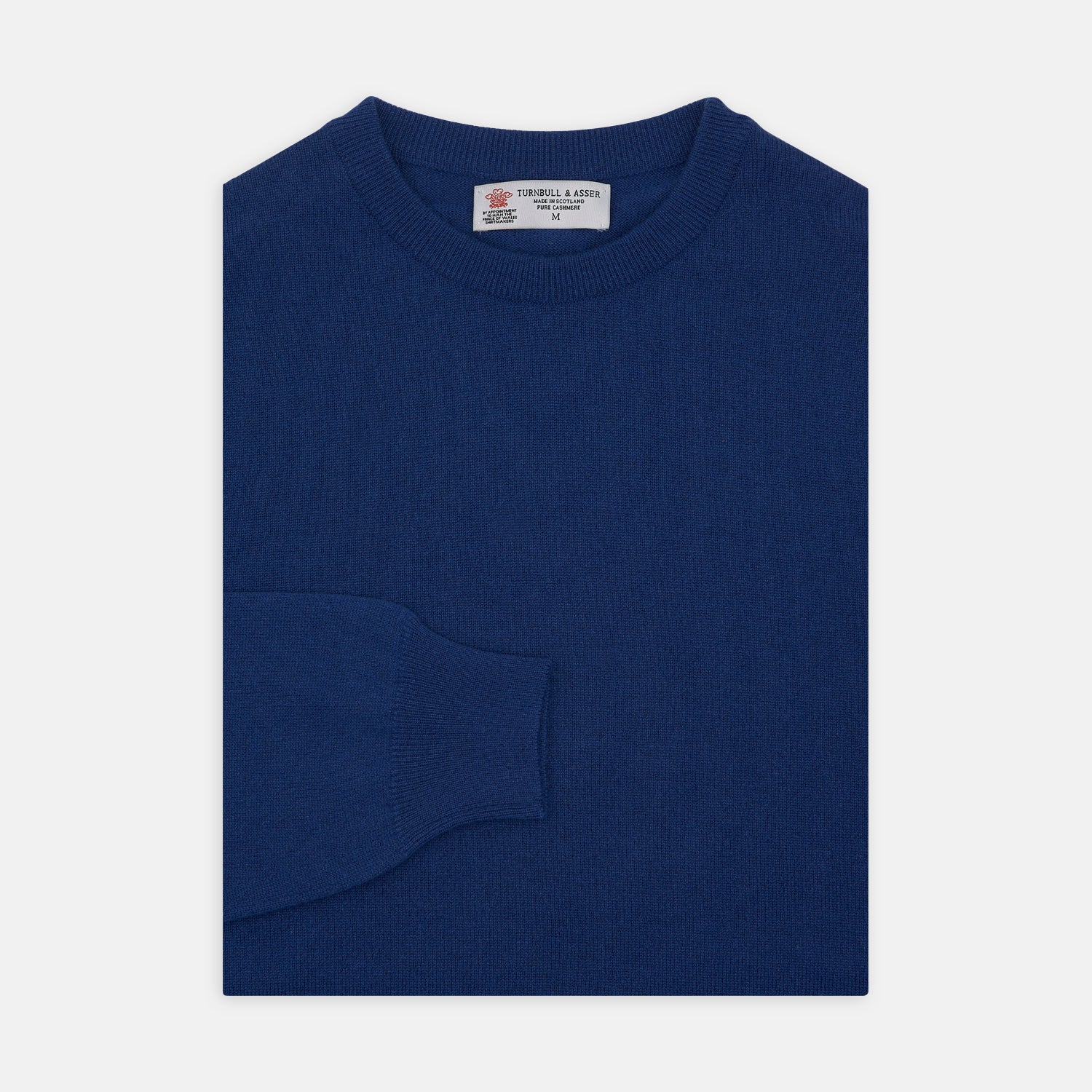 View 1 of product The Turnbull & Asser Blue Crew Neck Cashmere Jumper, neatly folded with ribbed collar and cuffs, is shown on a plain white background. A small label appears inside the collar.