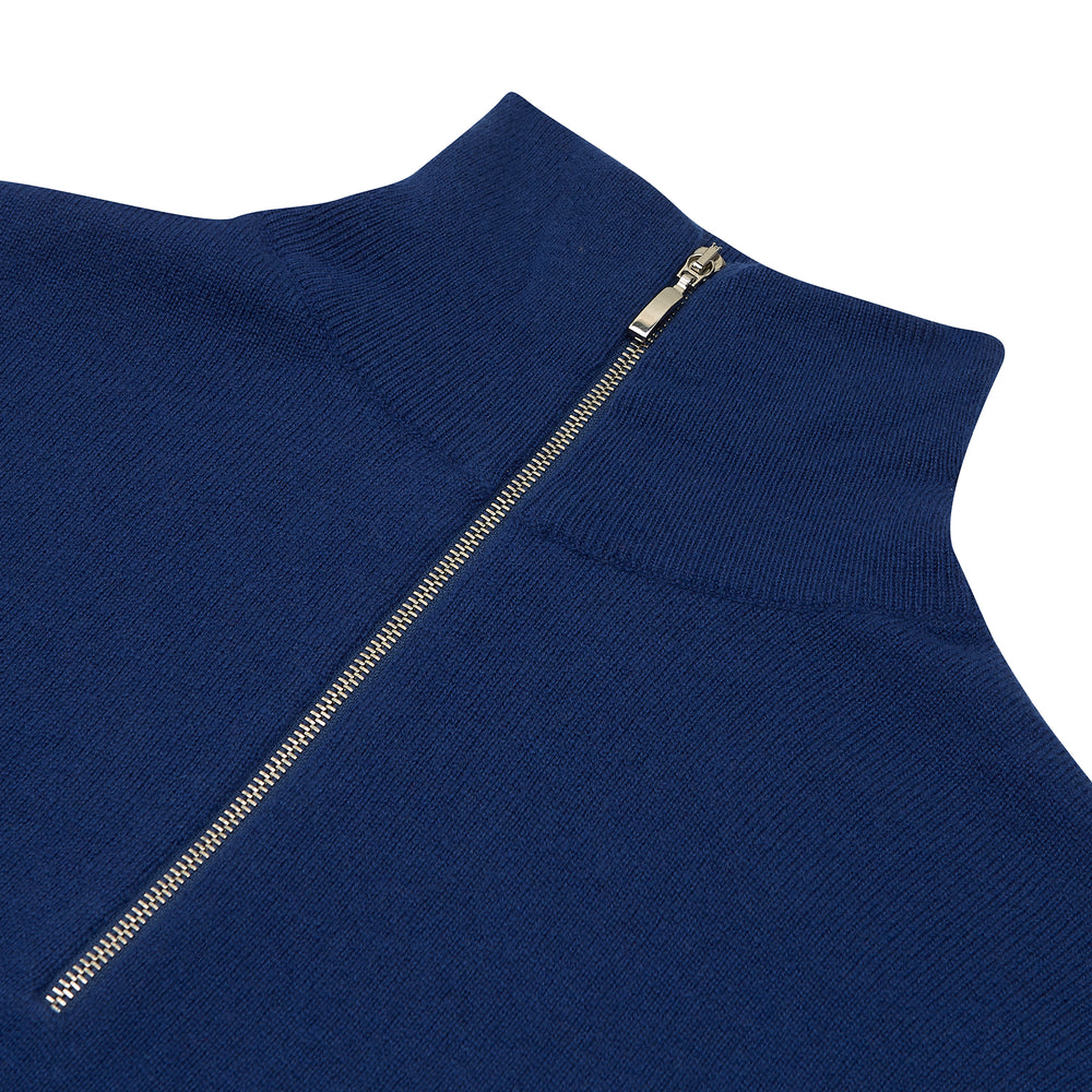 Turnbull & Asser’s Blue Half-Zip Cashmere Jumper with a high collar is neatly folded on a white background, its left sleeve partially tucked under—ideal for winter layering.