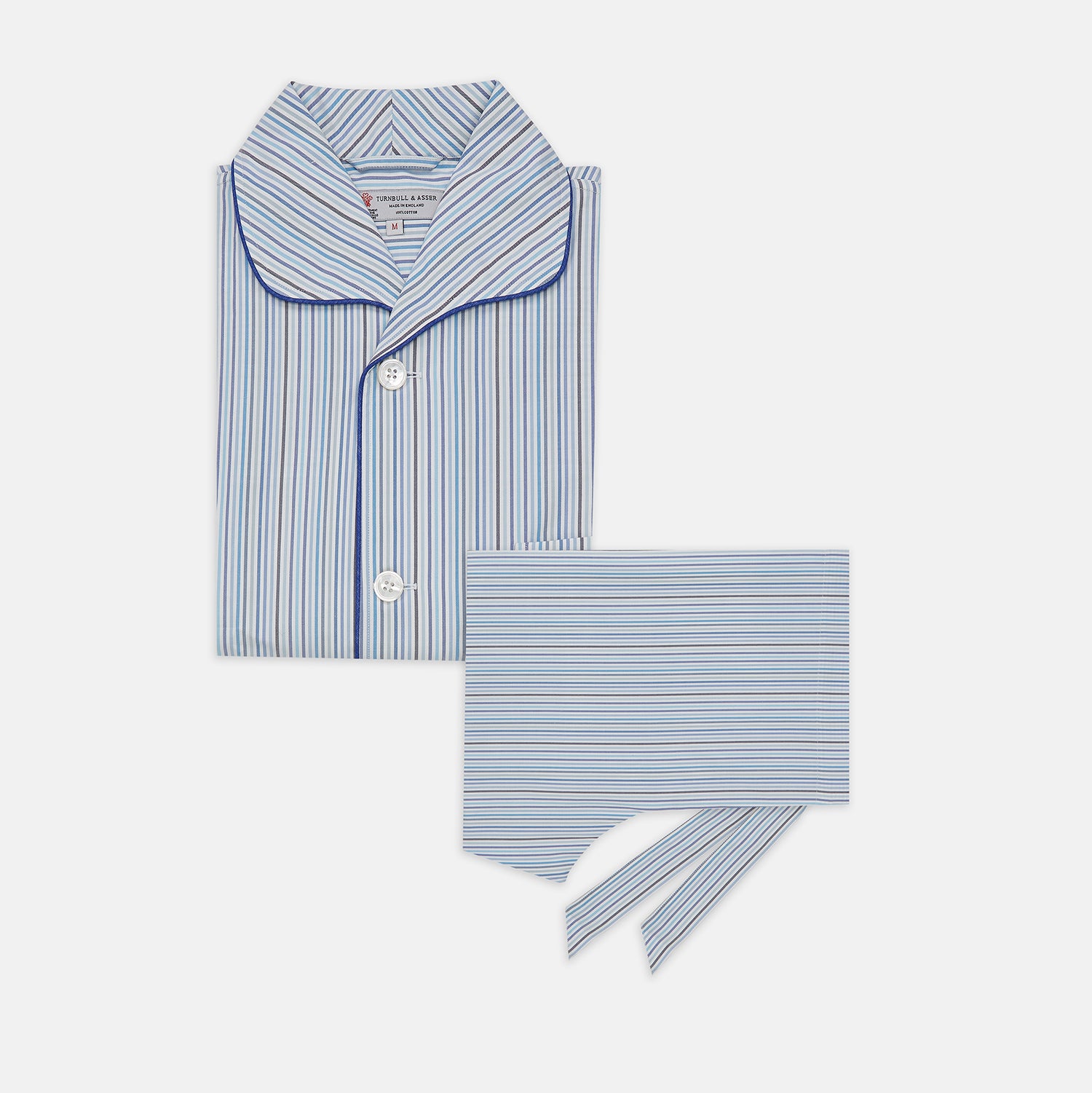 View 1 of product Turnbull & Asser’s Blue & White Twill Cotton Stripe Pyjama Set features a folded top with white buttons, dark blue piping, and a matching striped fabric belt, displayed on a white background.