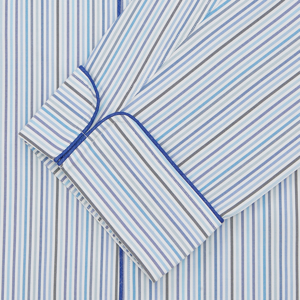 Turnbull & Asser’s Blue & White Twill Cotton Stripe Pyjama Set features a folded top with white buttons, dark blue piping, and a matching striped fabric belt, displayed on a white background.