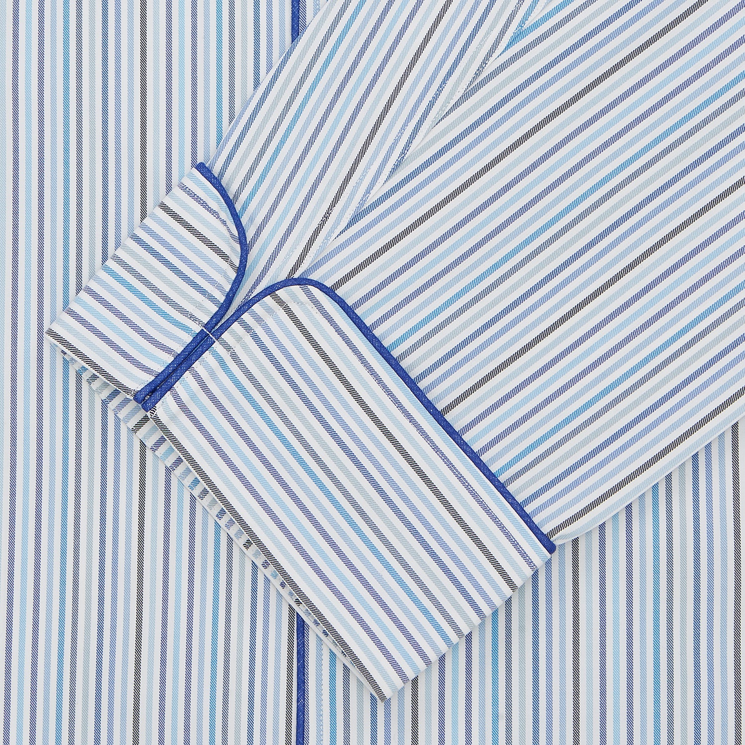 View 2 of product Turnbull & Asser’s Blue & White Twill Cotton Stripe Pyjama Set features a folded top with white buttons, dark blue piping, and a matching striped fabric belt, displayed on a white background.